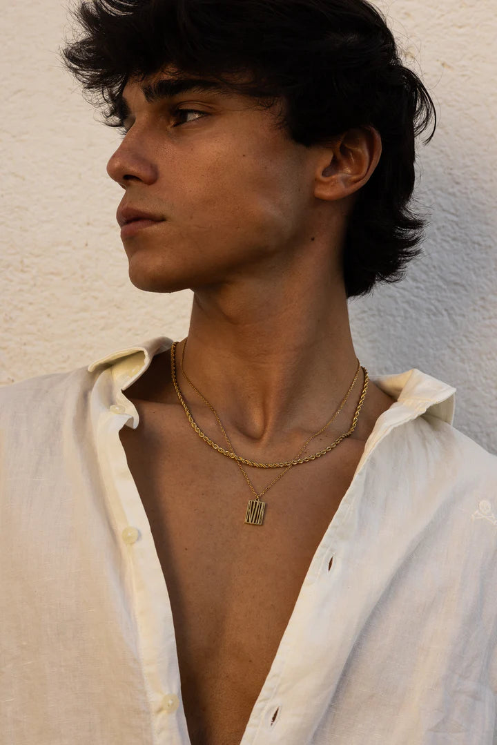 a man wearing a white shirt and a gold necklace