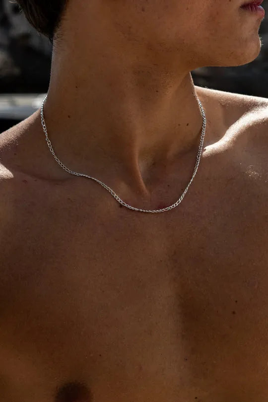 a shirtless man wearing a silver necklace