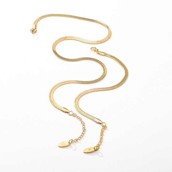 a gold necklace with a long chain on a white background