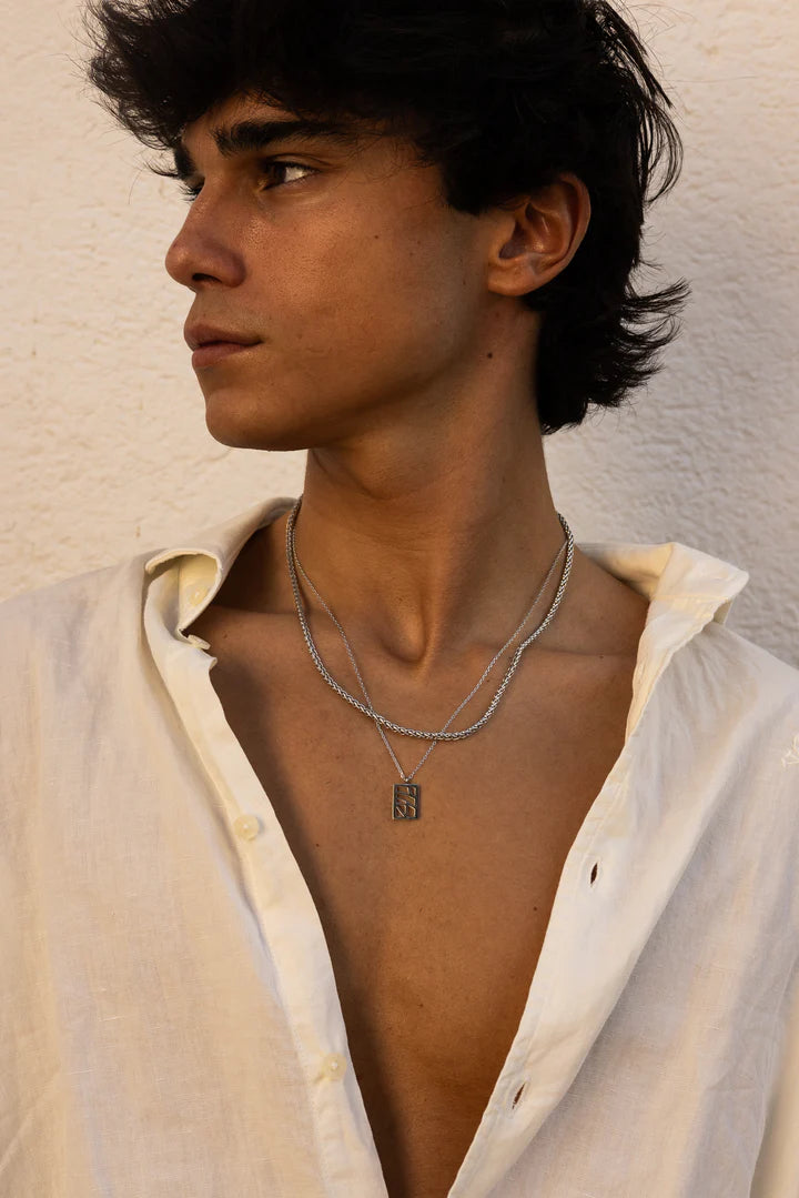 a man wearing a white shirt and a silver necklace