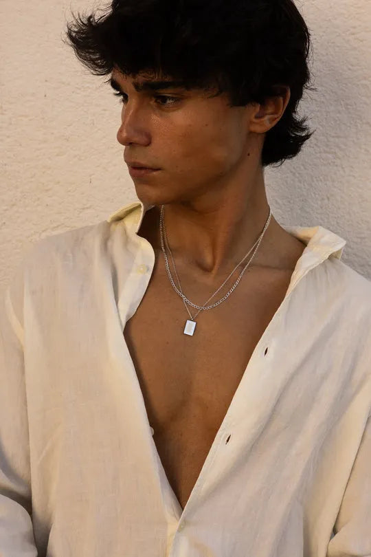 a man wearing a white shirt and a silver necklace