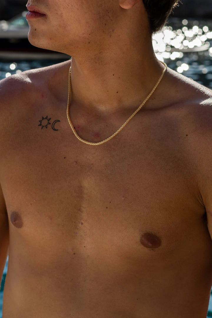 a shirtless man standing in front of a body of water