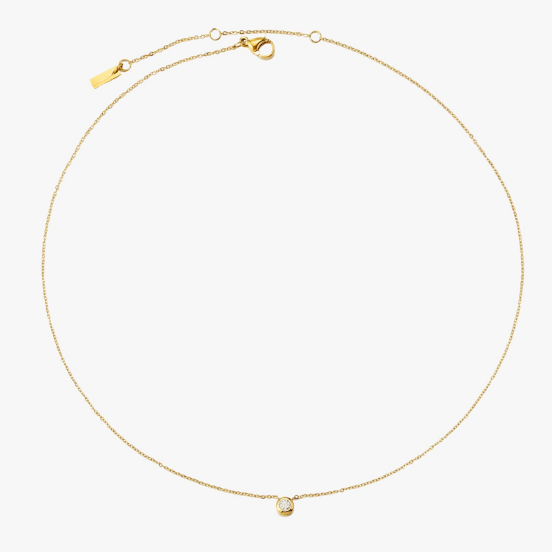 a gold necklace with a heart on a white background