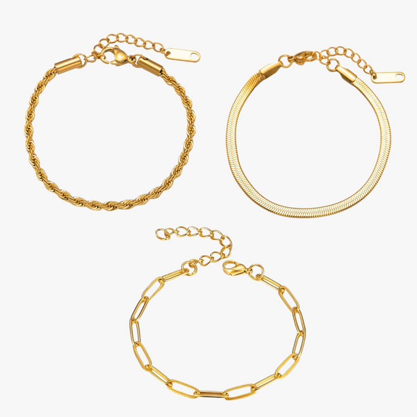 a set of three gold bracelets on a white background