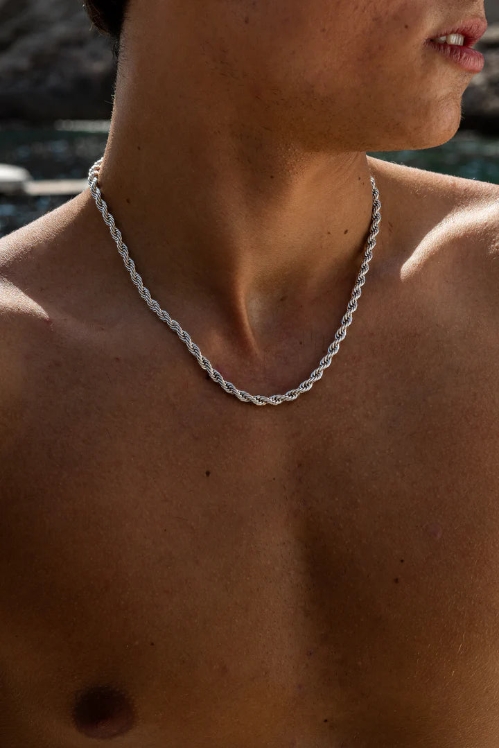 a shirtless man wearing a silver chain necklace