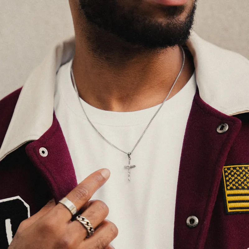 a close up of a person wearing a jacket and a cross necklace