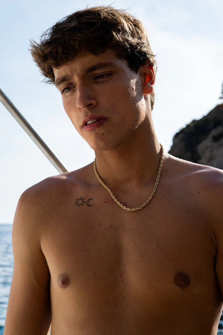 a shirtless young man standing next to a body of water